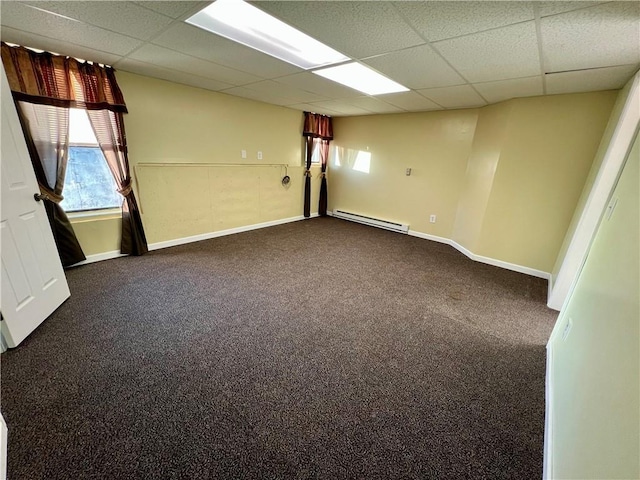 empty room featuring baseboard heating, carpet, and a drop ceiling