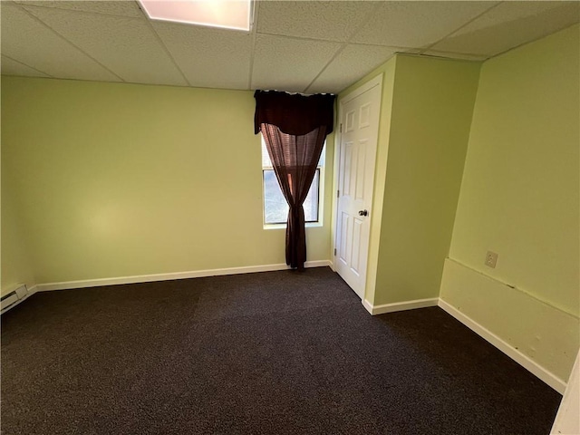 spare room with a drop ceiling and dark colored carpet