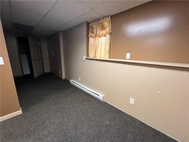 unfurnished room with dark colored carpet, a baseboard heating unit, and a drop ceiling