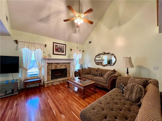 living room with ceiling fan, hardwood / wood-style flooring, a stone fireplace, and a healthy amount of sunlight