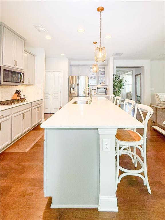810 Pressing Dr, Alpharetta, GA 30004 - kitchen featuring appliances with stainless steel finishes, a sink, a breakfast bar, a center island with sink, and hanging light fixtures
