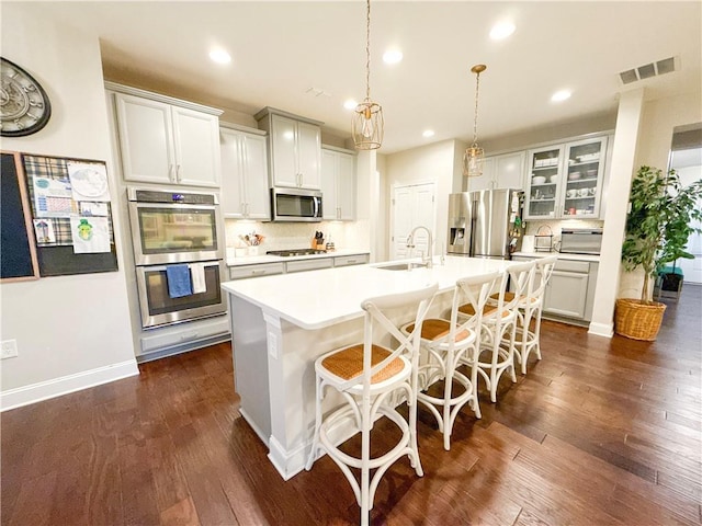 810 Pressing Dr, Alpharetta, GA 30004 - kitchen with stainless steel appliances, a kitchen island with sink, dark wood-type flooring, recessed lighting, and glass insert cabinets