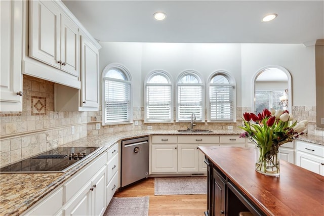 kitchen with dishwasher, light stone countertops, black electric cooktop, sink, and white cabinetry