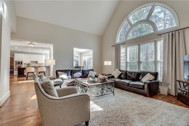 living room with light wood-type flooring and high vaulted ceiling