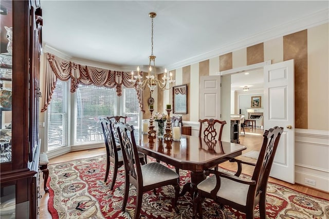 dining space featuring light wood-type flooring, crown molding, and an inviting chandelier