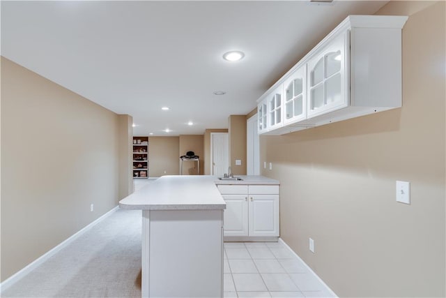 kitchen featuring sink, kitchen peninsula, white cabinets, and light tile patterned flooring