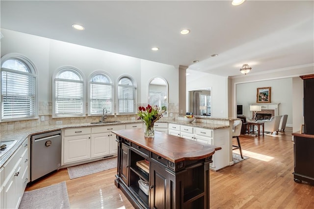 kitchen with a center island, sink, light stone counters, dishwasher, and white cabinets