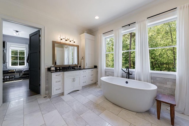bathroom with a soaking tub, ensuite bathroom, vanity, and ornamental molding