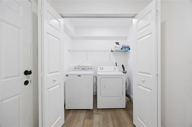 clothes washing area with independent washer and dryer and light hardwood / wood-style flooring