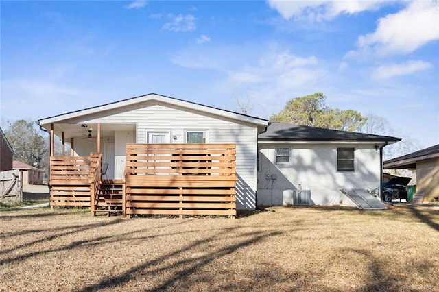 rear view of house with a wooden deck, cooling unit, and a lawn