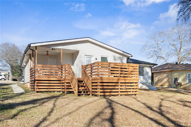 view of front of home with ceiling fan, a wooden deck, and a front lawn