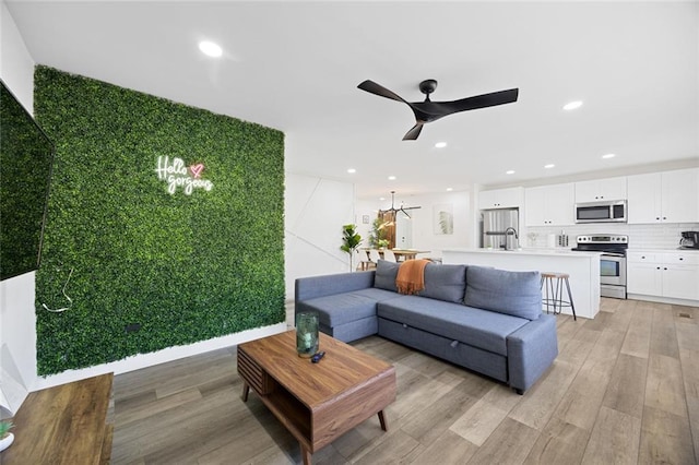 living room with light wood-type flooring, ceiling fan, and sink