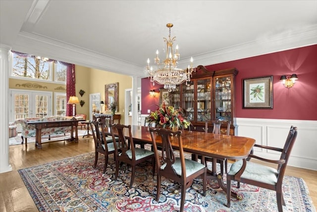 dining space featuring french doors, decorative columns, hardwood / wood-style flooring, and ornamental molding