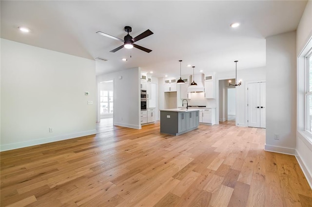 6073 Rockingham Way, Gainesville, GA 30506 - kitchen with a kitchen island with sink, light wood-style floors, open floor plan, white cabinets, and ceiling fan with notable chandelier