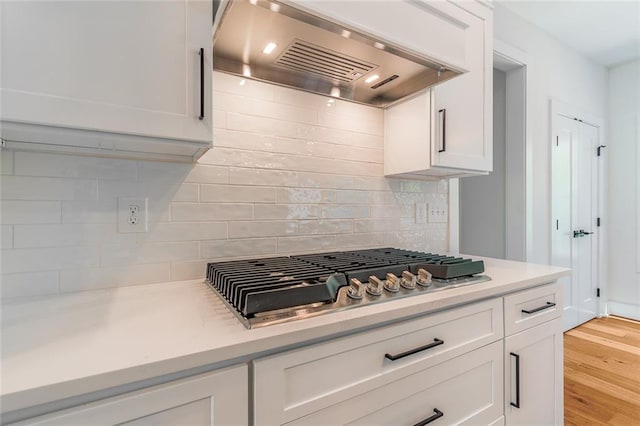 6073 Rockingham Way, Gainesville, GA 30506 - kitchen featuring stainless steel gas cooktop, white cabinets, premium range hood, and tasteful backsplash