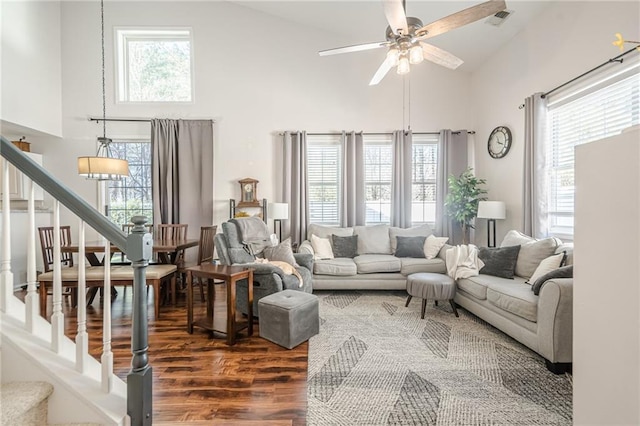 living room featuring visible vents, dark wood-type flooring, ceiling fan, stairway, and plenty of natural light