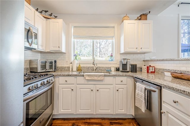 kitchen featuring plenty of natural light, white cabinets, stainless steel appliances, and a sink