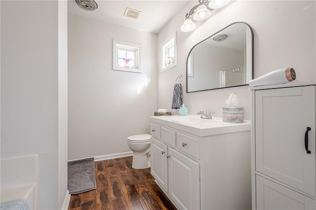 bathroom with visible vents, baseboards, toilet, wood finished floors, and vanity