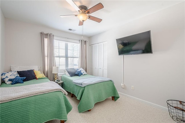 carpeted bedroom with visible vents, baseboards, a closet, and ceiling fan