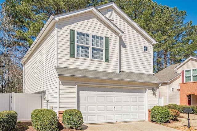 view of front of property featuring a garage, a shingled roof, concrete driveway, and fence