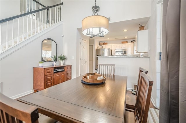 dining area with stairway, recessed lighting, baseboards, and a towering ceiling