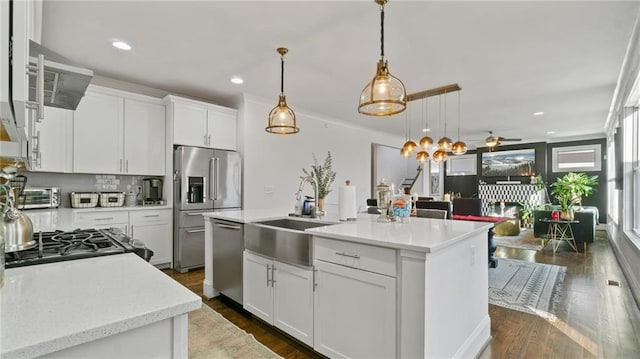 kitchen with a center island with sink, white cabinets, hanging light fixtures, ceiling fan, and appliances with stainless steel finishes