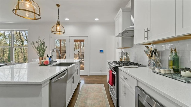 kitchen with decorative backsplash, appliances with stainless steel finishes, sink, white cabinetry, and hanging light fixtures