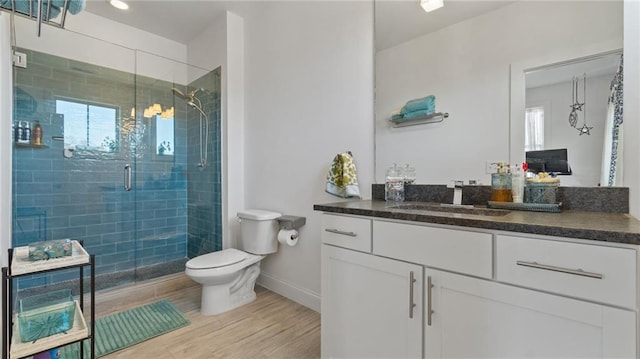 bathroom featuring a shower with door, vanity, hardwood / wood-style floors, and toilet