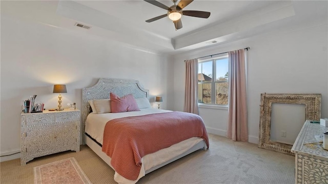 carpeted bedroom with a raised ceiling and ceiling fan