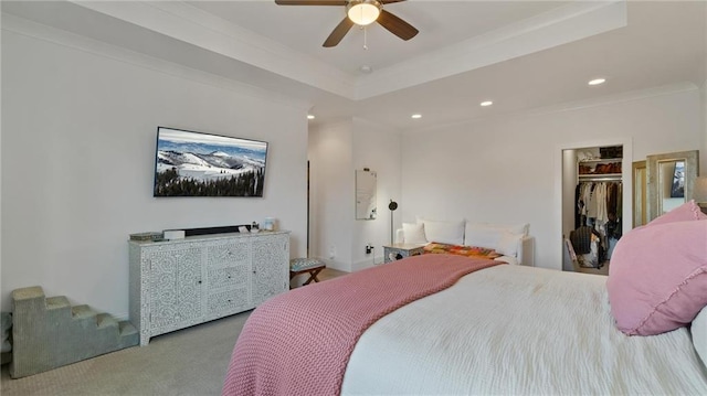 carpeted bedroom with a closet, a spacious closet, ceiling fan, and crown molding