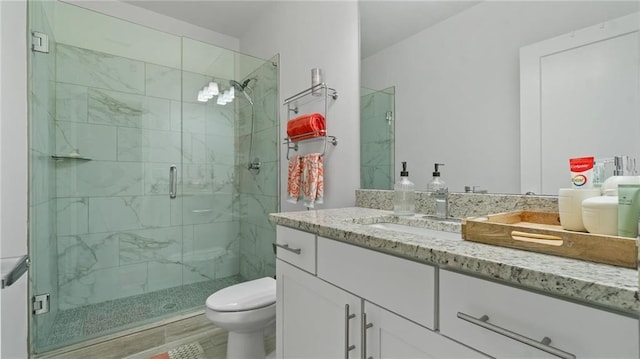 bathroom featuring vanity, toilet, and a shower with door