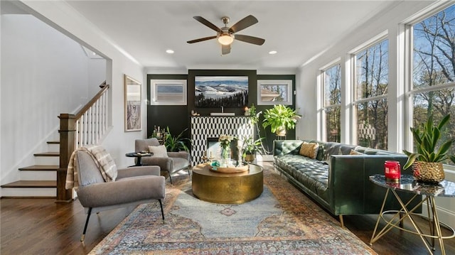 sitting room featuring ceiling fan, dark hardwood / wood-style flooring, ornamental molding, and a fireplace