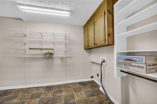 clothes washing area featuring hookup for a washing machine, cabinets, a textured ceiling, and dark tile floors