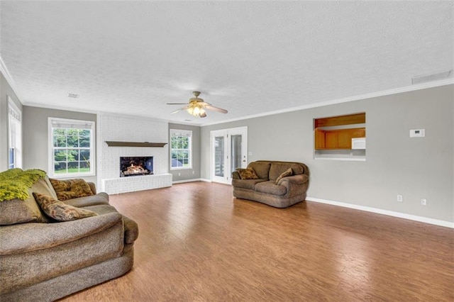 living room featuring brick wall, a fireplace, hardwood / wood-style flooring, ornamental molding, and a textured ceiling