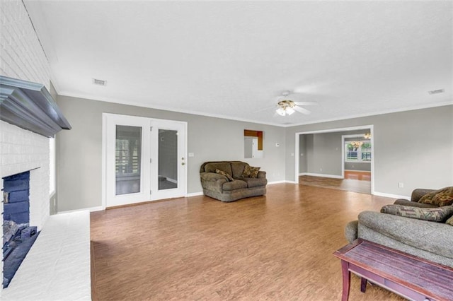 living room featuring a brick fireplace, ceiling fan, crown molding, and wood-type flooring