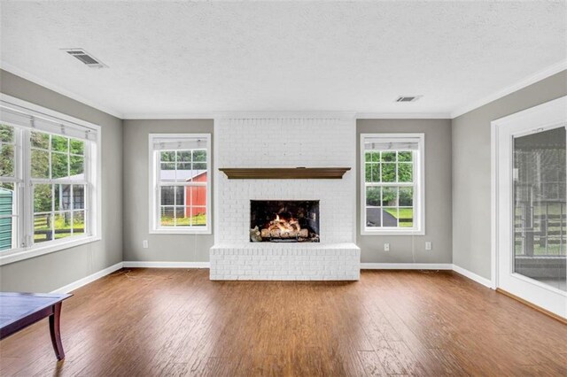 unfurnished living room featuring a brick fireplace, a wealth of natural light, and wood-type flooring