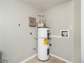 utility room featuring electric panel and water heater