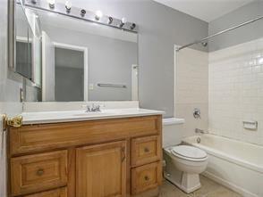 full bathroom featuring vanity, tiled shower / bath, and toilet