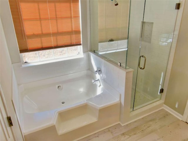 full bathroom featuring a shower stall, baseboards, a bath, and wood finished floors