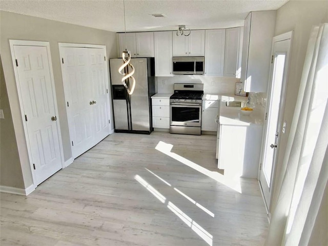 kitchen featuring light wood-style flooring, visible vents, appliances with stainless steel finishes, and light countertops