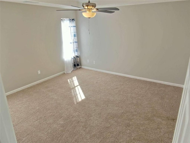 carpeted spare room with baseboards and a ceiling fan