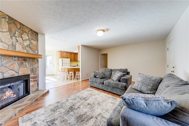 living area featuring light wood finished floors, a fireplace, and a textured ceiling