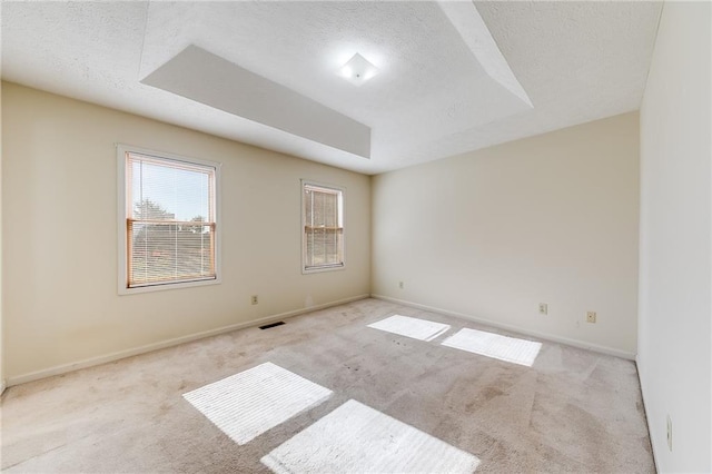 carpeted spare room featuring a textured ceiling, visible vents, and baseboards