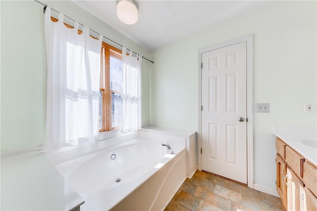 full bath with stone finish flooring, a garden tub, vanity, and baseboards