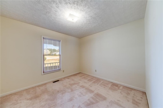 unfurnished room with baseboards, visible vents, a textured ceiling, and light colored carpet