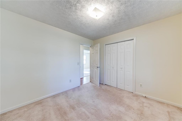 unfurnished bedroom with a textured ceiling, a closet, baseboards, and carpet flooring