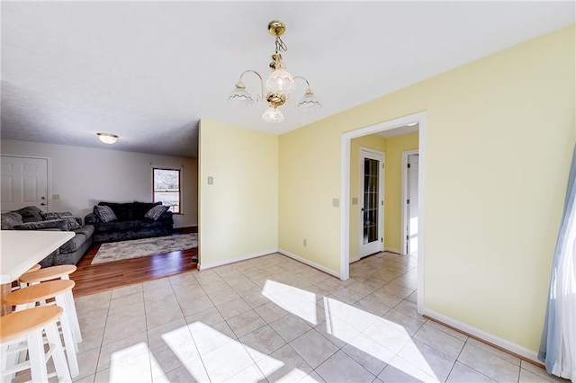 dining area featuring a notable chandelier, baseboards, and light tile patterned floors