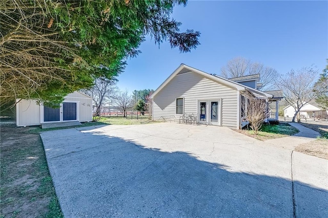 view of side of property with driveway, an outbuilding, and french doors