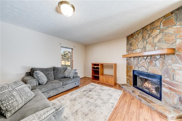 living room featuring a stone fireplace and wood finished floors