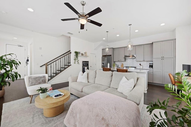 living room featuring dark wood-type flooring and ceiling fan